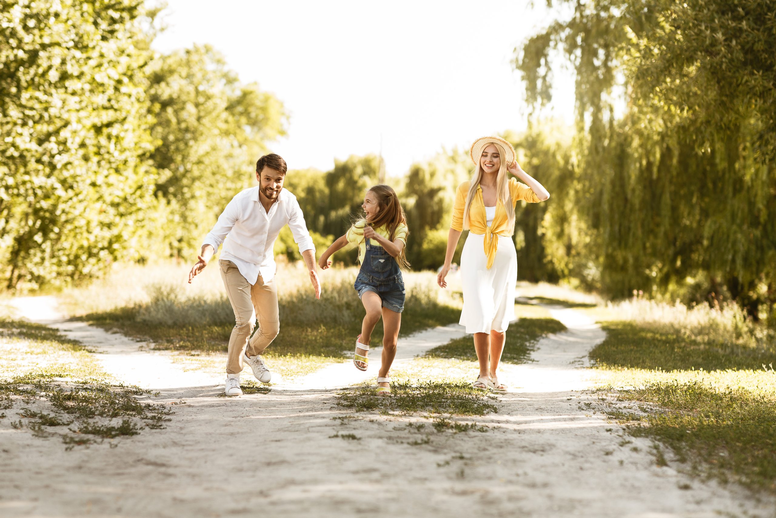 Family spending time in countryside. Girl running from father, having fun outdoors